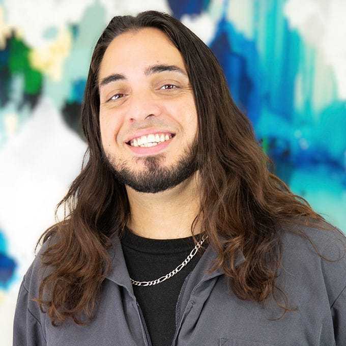 Portrait of Zeke Santos, a professional stylist at Pura Vida Salon, showcasing their expertise and style.